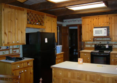 Rustic kitchen before renovation showing outdated cabinetry and appliances