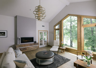 Fireplace on marble hearth in living room. Large window with view of lake.