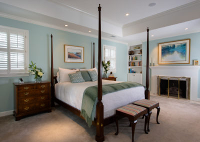 Bedroom with four-post bed and light blue walls plus traditional period mantle and fireplace